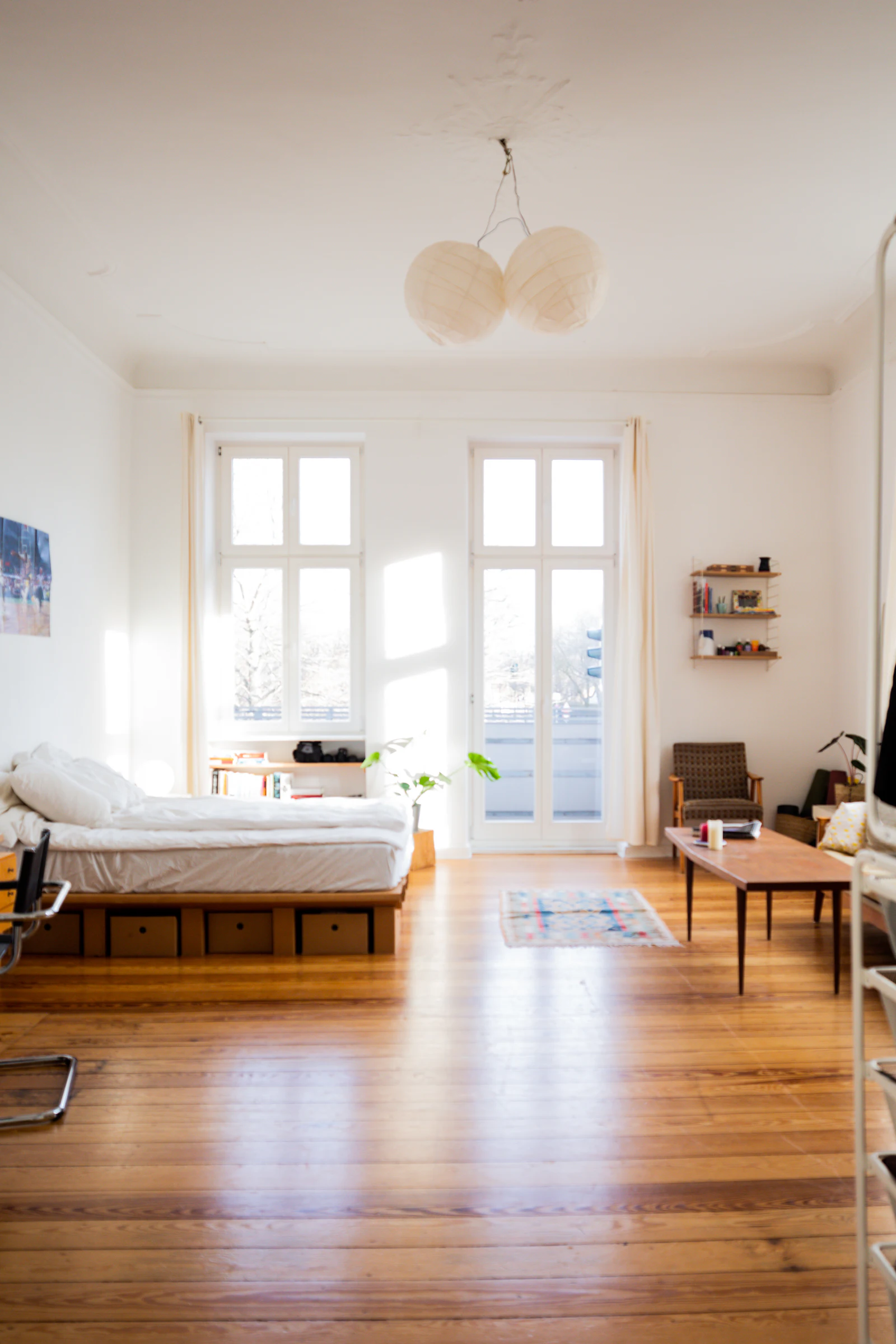 A bedroom in a compact unit, bed set beside a tall window