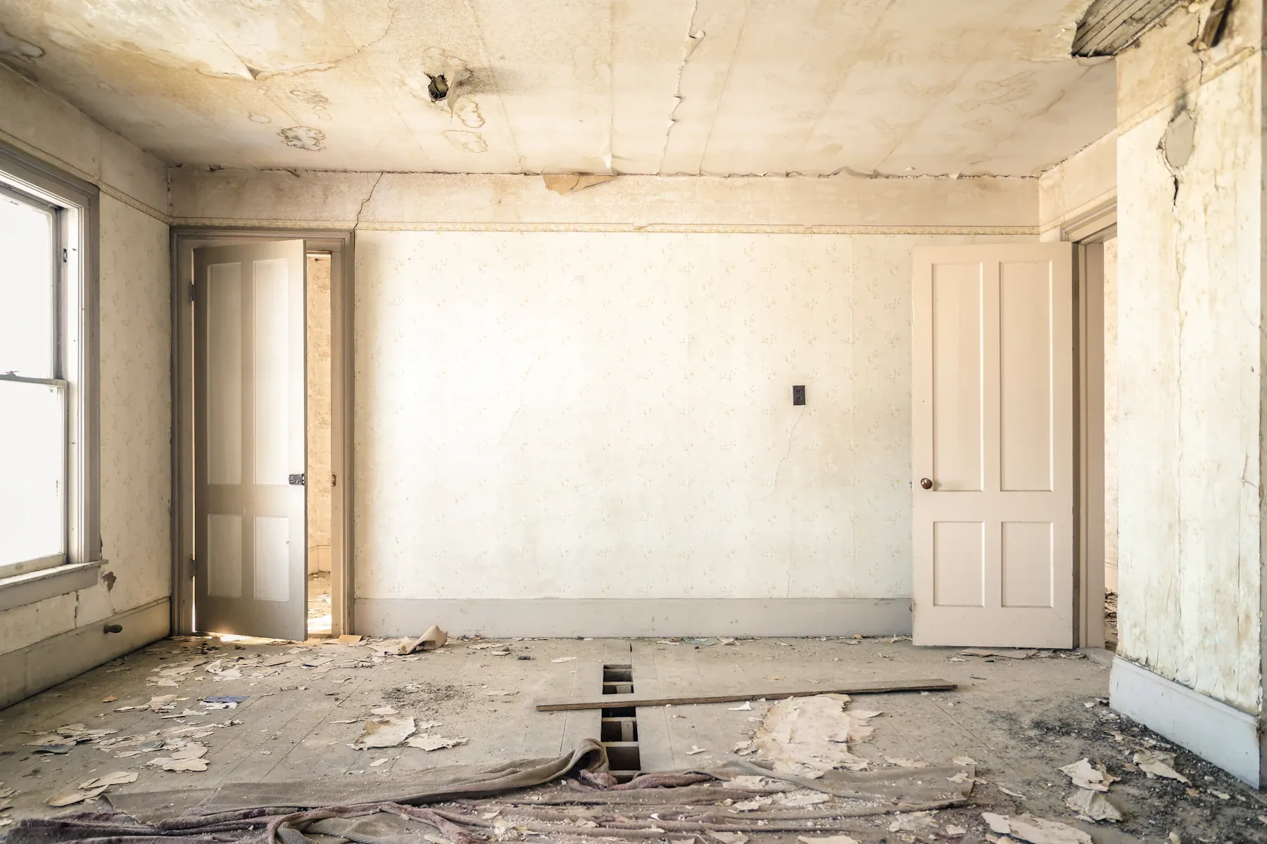 A stripped room with damaged wall finishes and the doors standing open