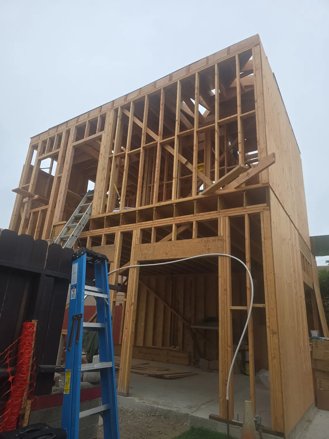 A two-story timber frame with sheathing going on to the upper walls
