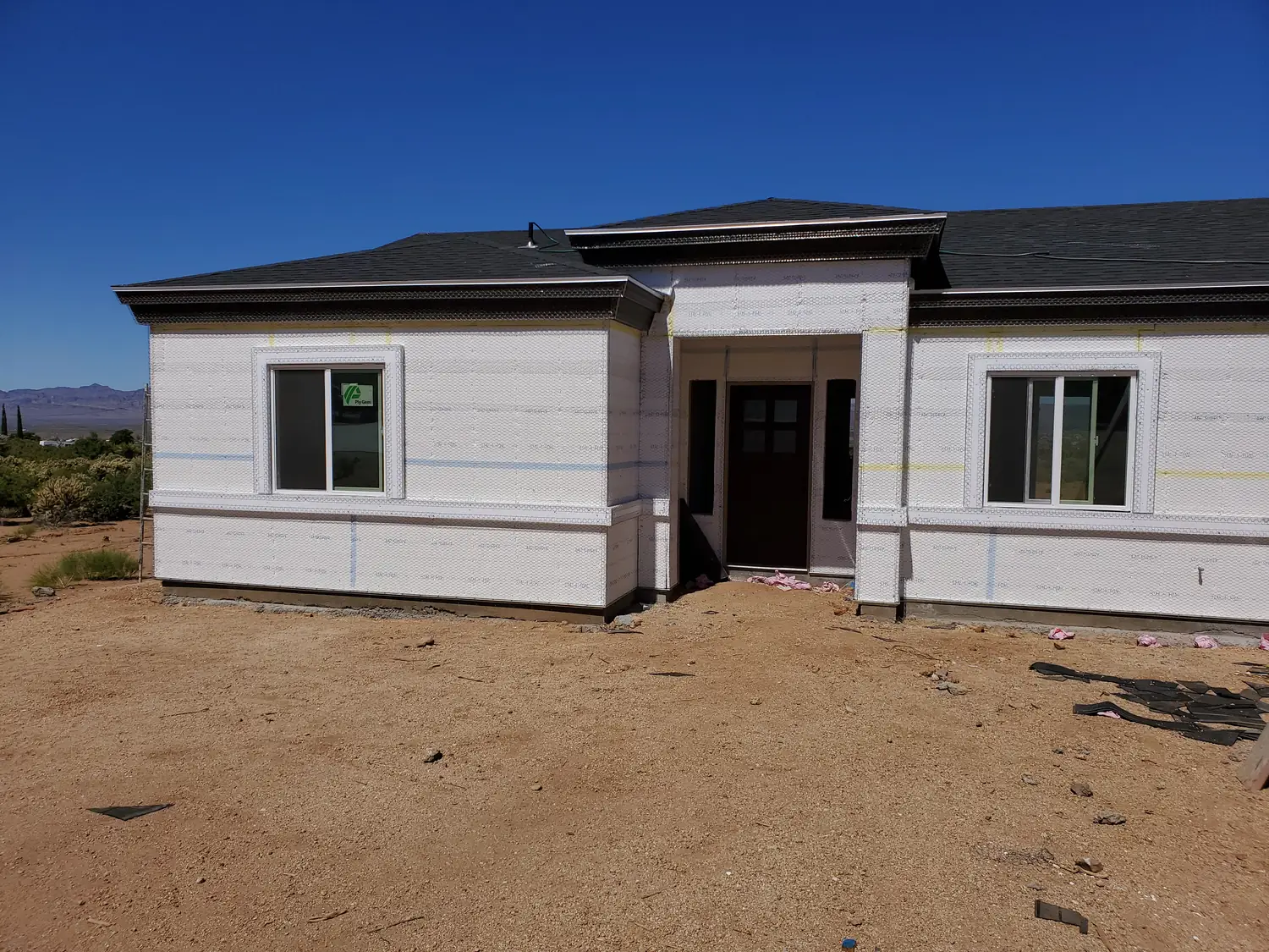 The front of a new build in housewrap with the windows and entry door fitted
