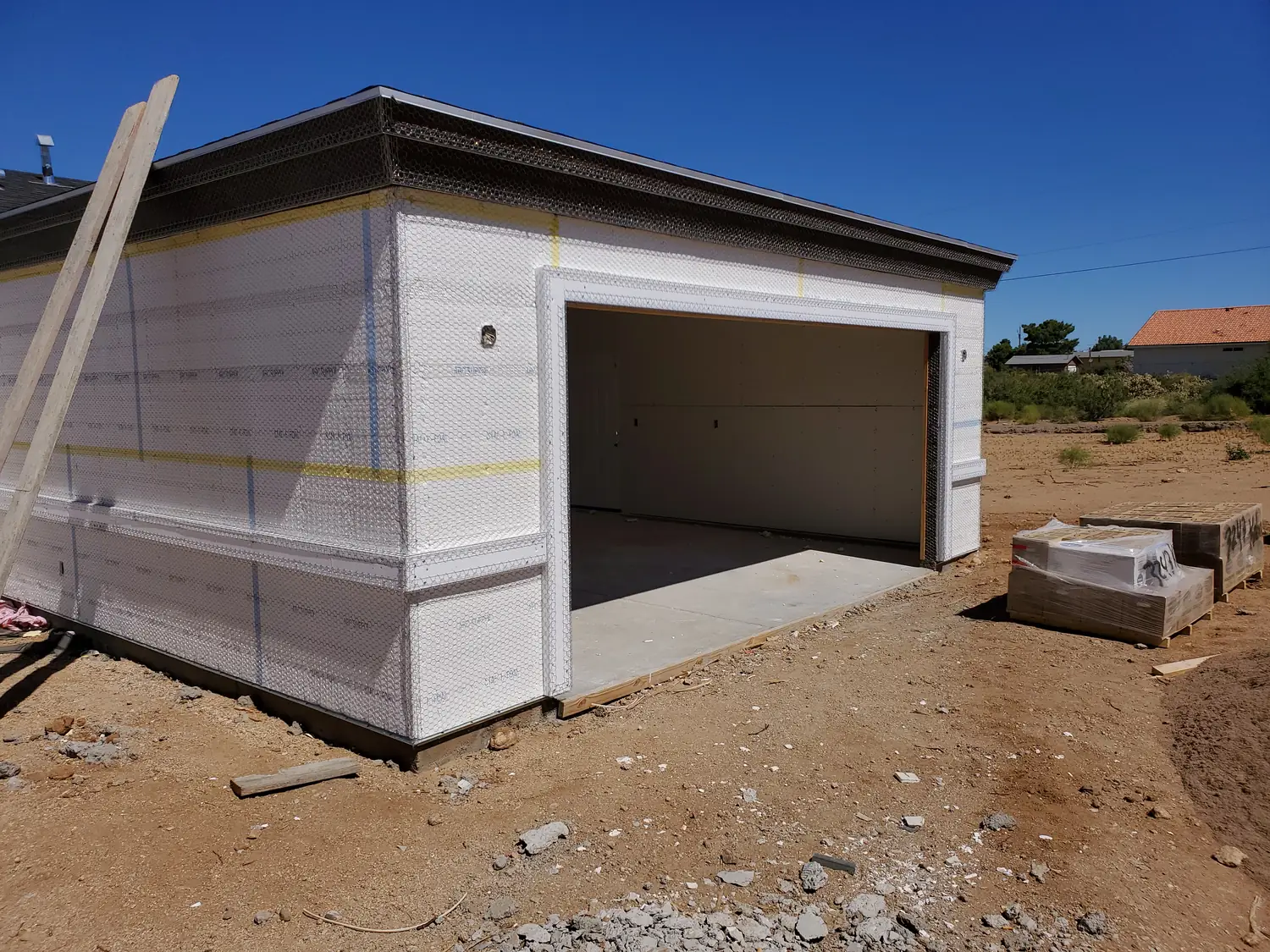 A new build at housewrap stage with the garage opening framed and its apron poured