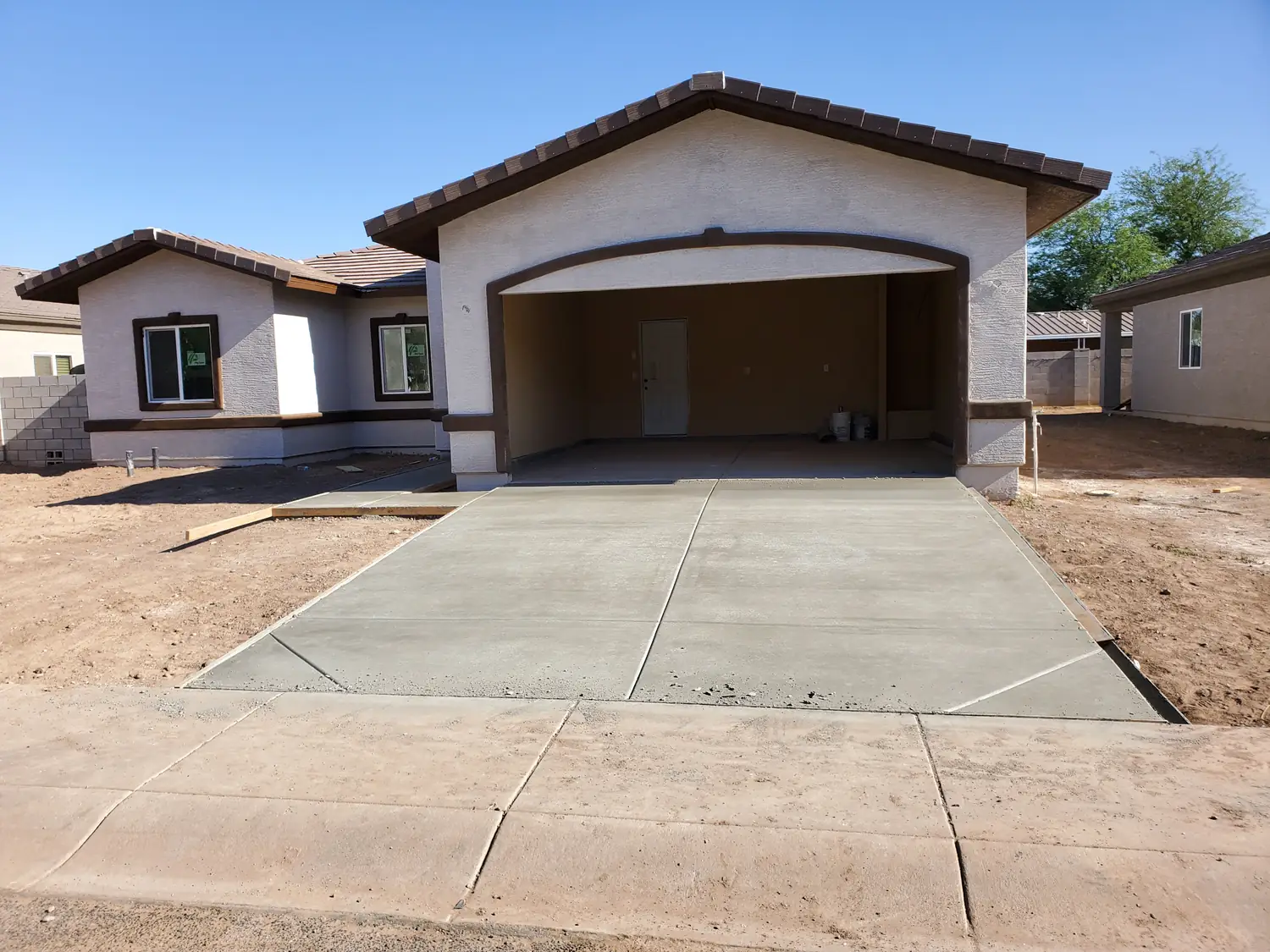 A new house with the stucco and roof tiles on and the driveway poured, the garage opening still without its door